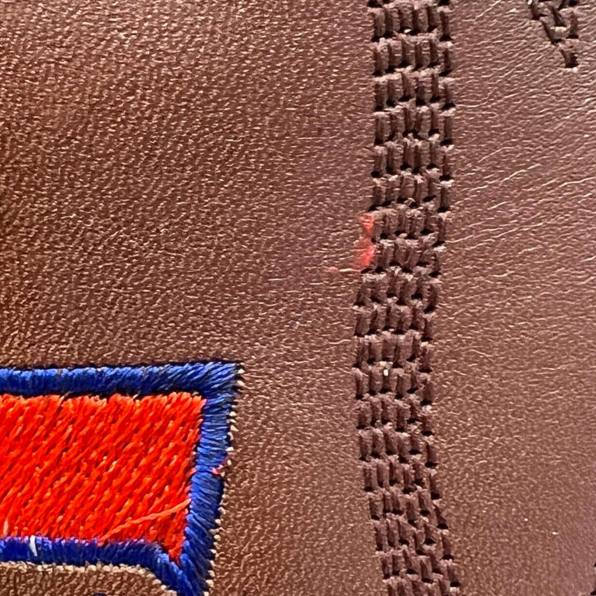 Brown leather boot with laced stitch pattern and partial red-blue embroidery