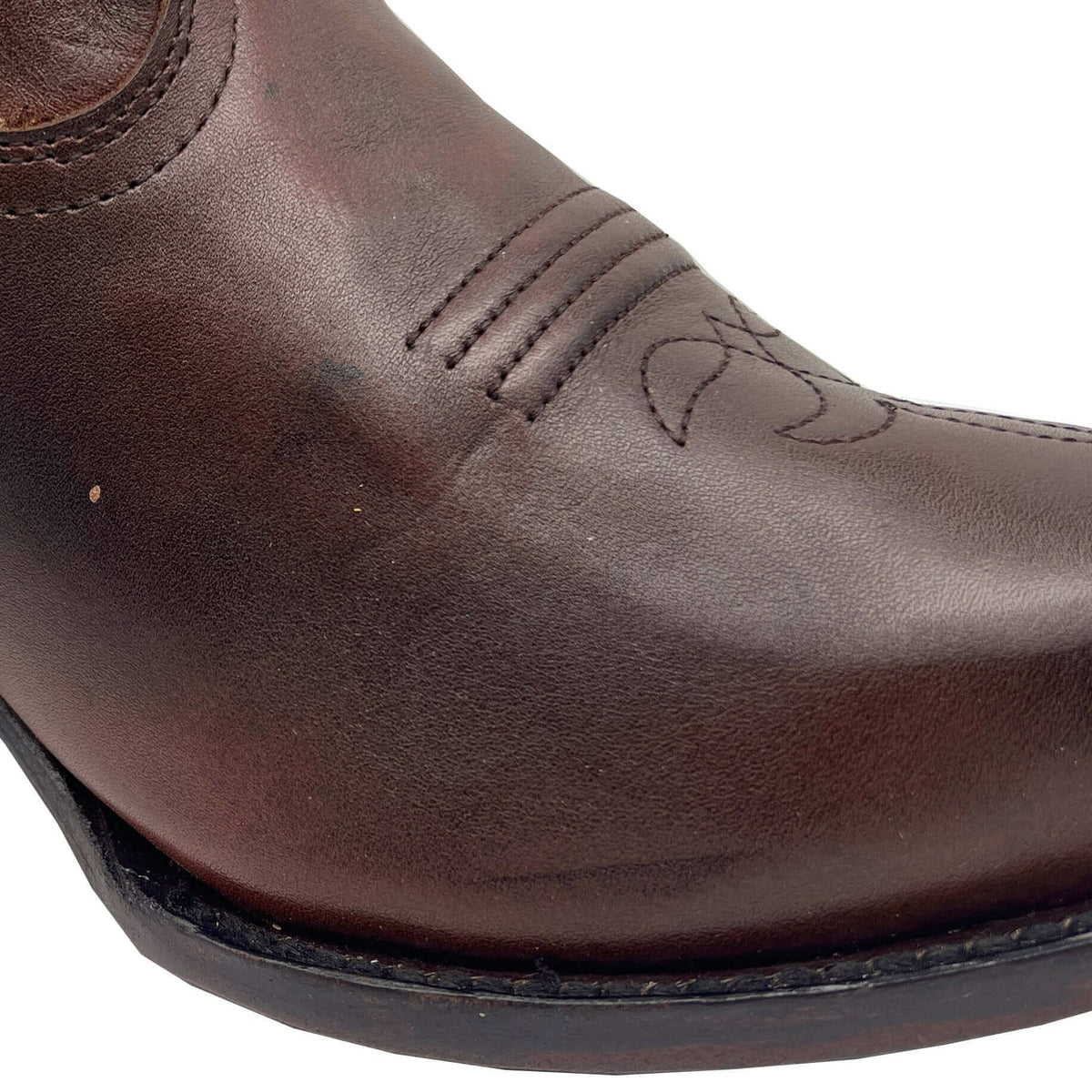 Brown leather boot toe and front seam with curved stitch detail