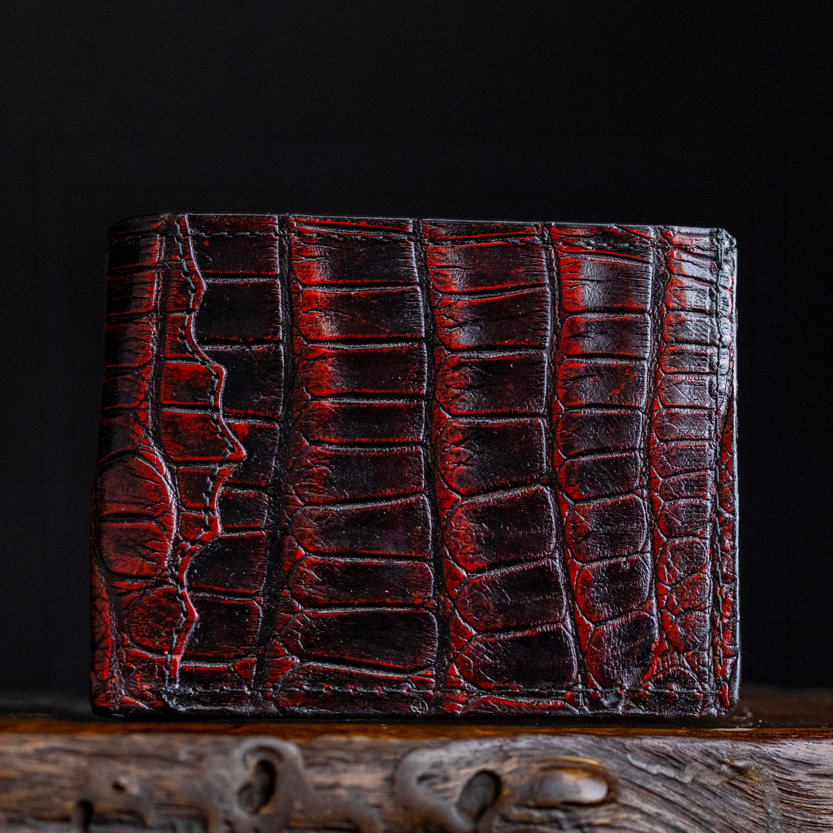 Red-burgundy alligator-style billfold close-up with crocodile texture and stitched panels