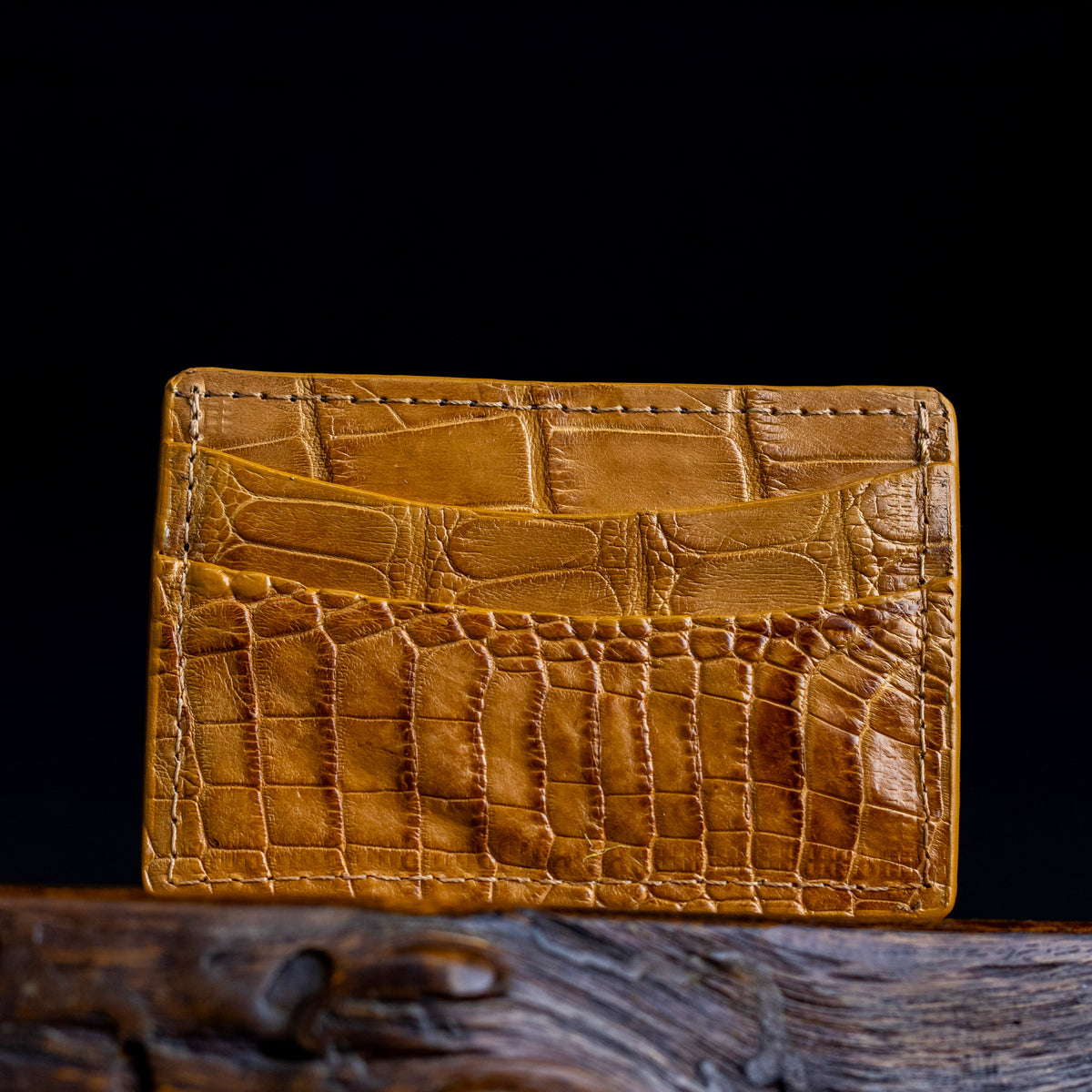 Tan embossed leather card holder with stitched edges and slim front