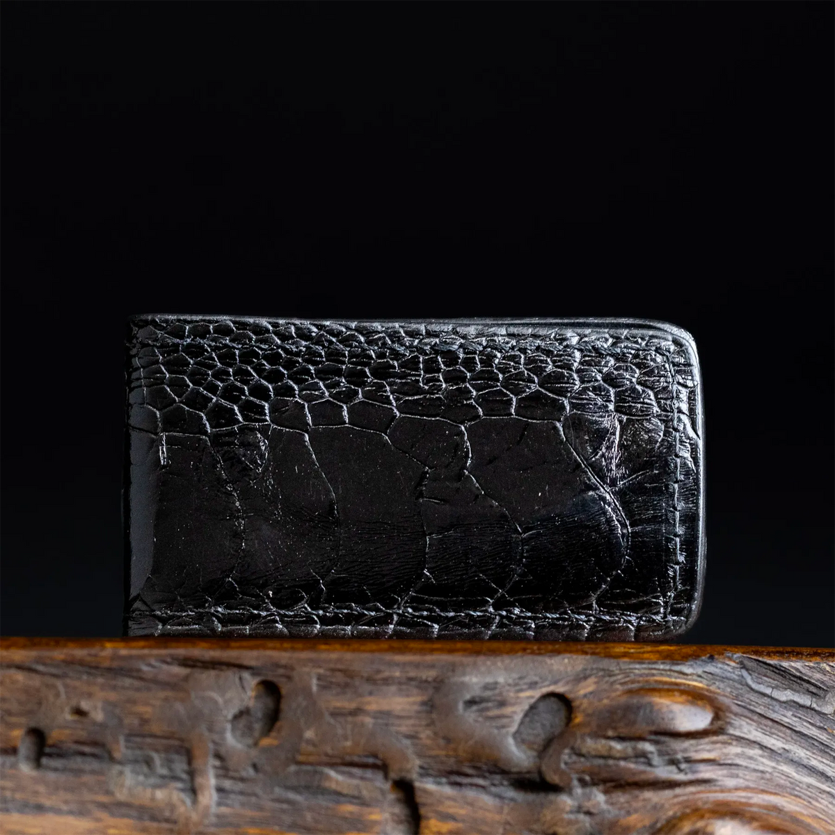 Black ostrich leather money clip with textured grain and metal hinge