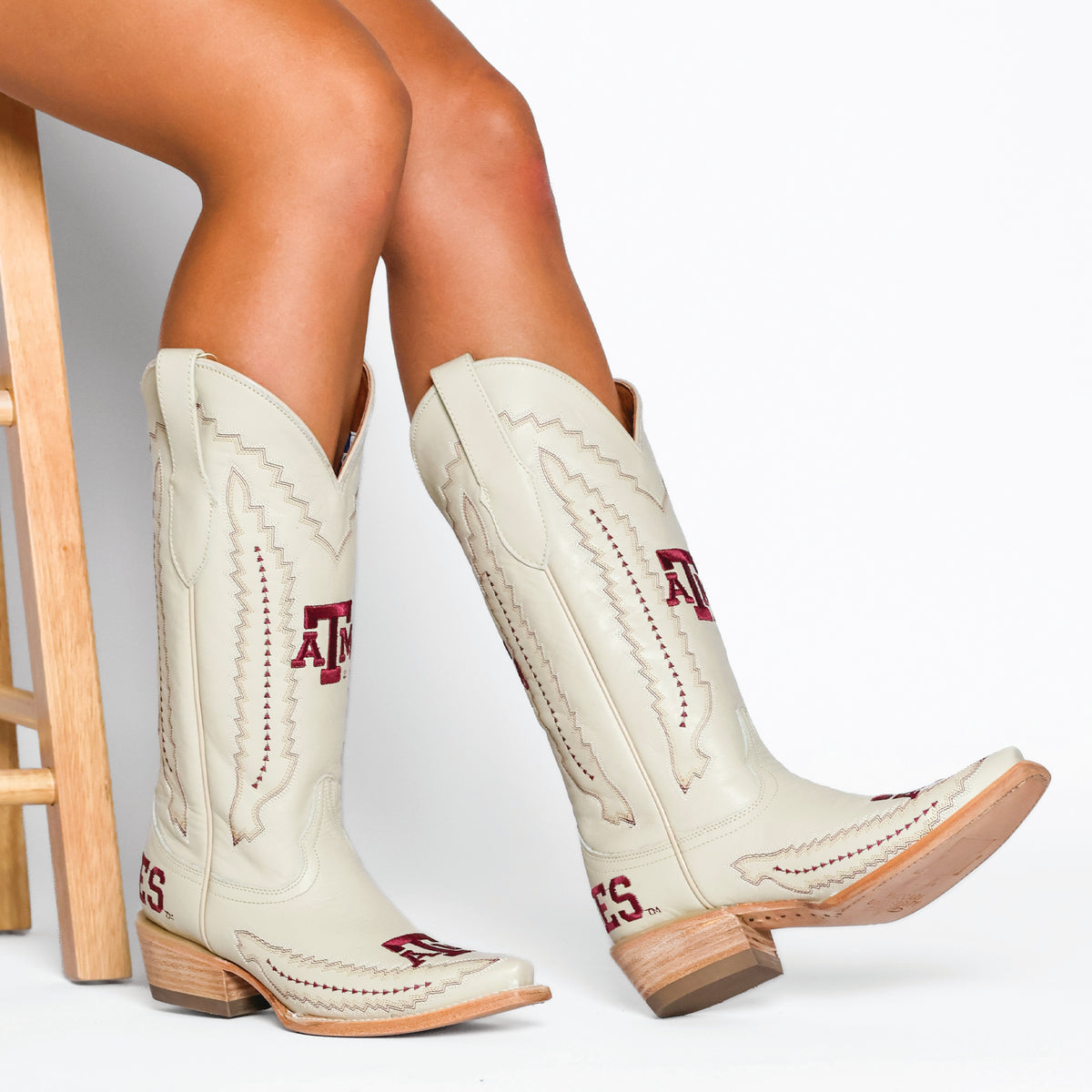 Cream cowboy boots on legs, western stitching with red AG logo and block heel