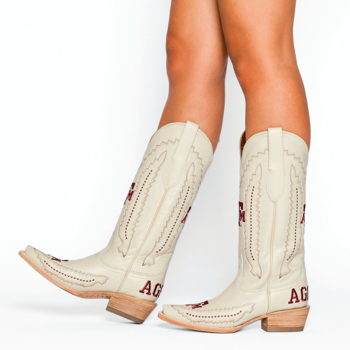Cream cowboy boots with stitched patterns, red trim, and wooden block heel