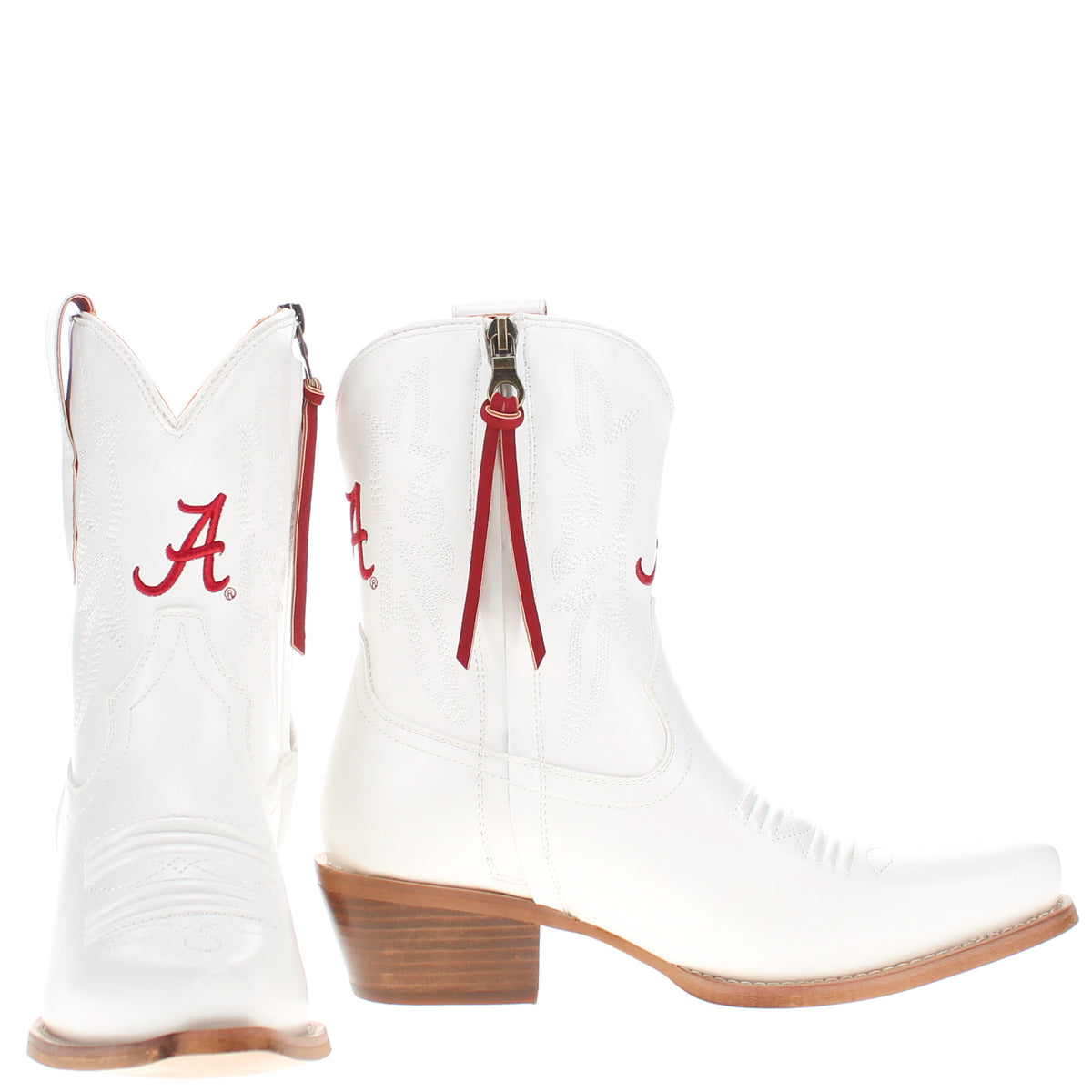 Pair of white cowboy boots, side-by-side with red tassel straps and brown heels