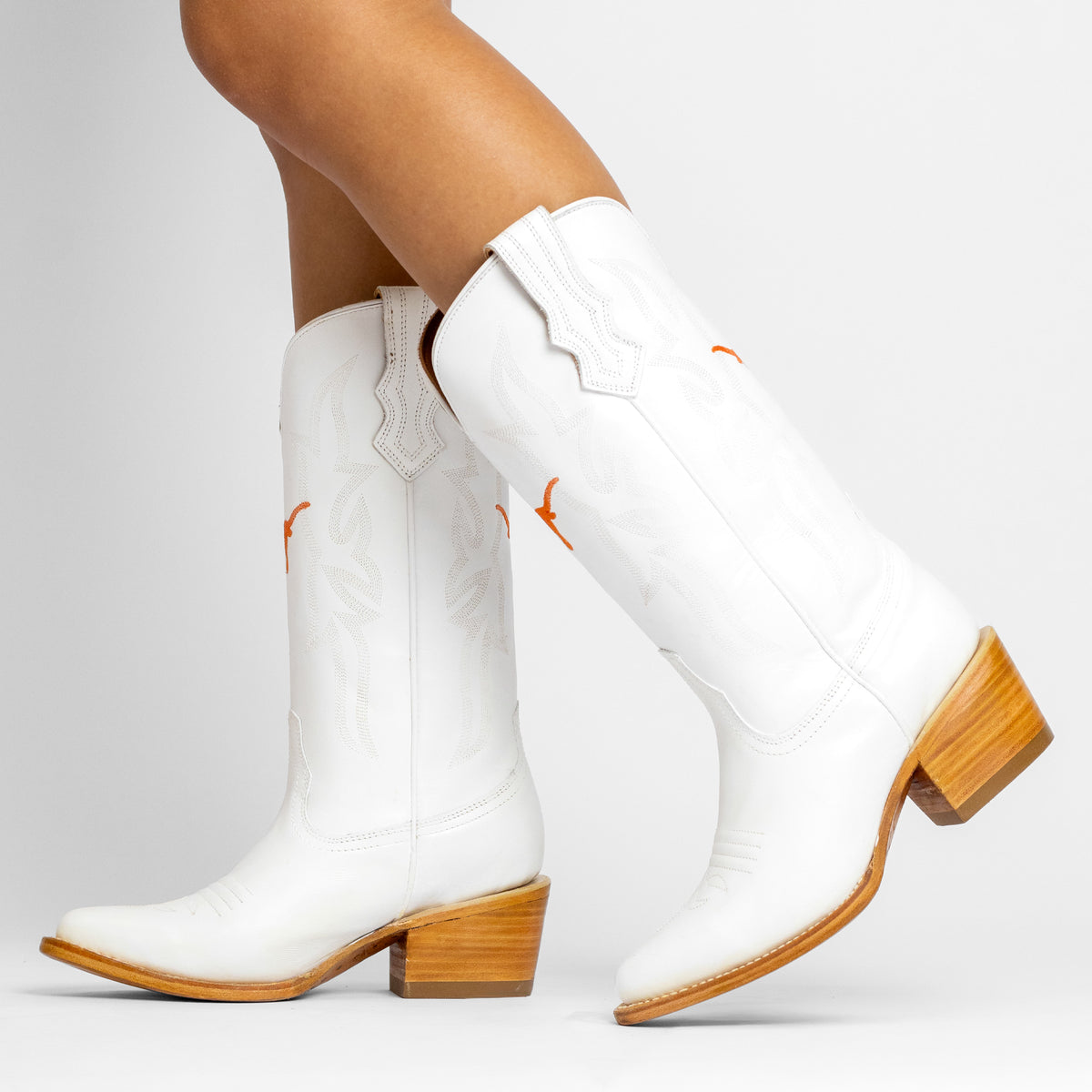 White cowboy boots with orange stitched logo, mid-calf shaft and wood block heel
