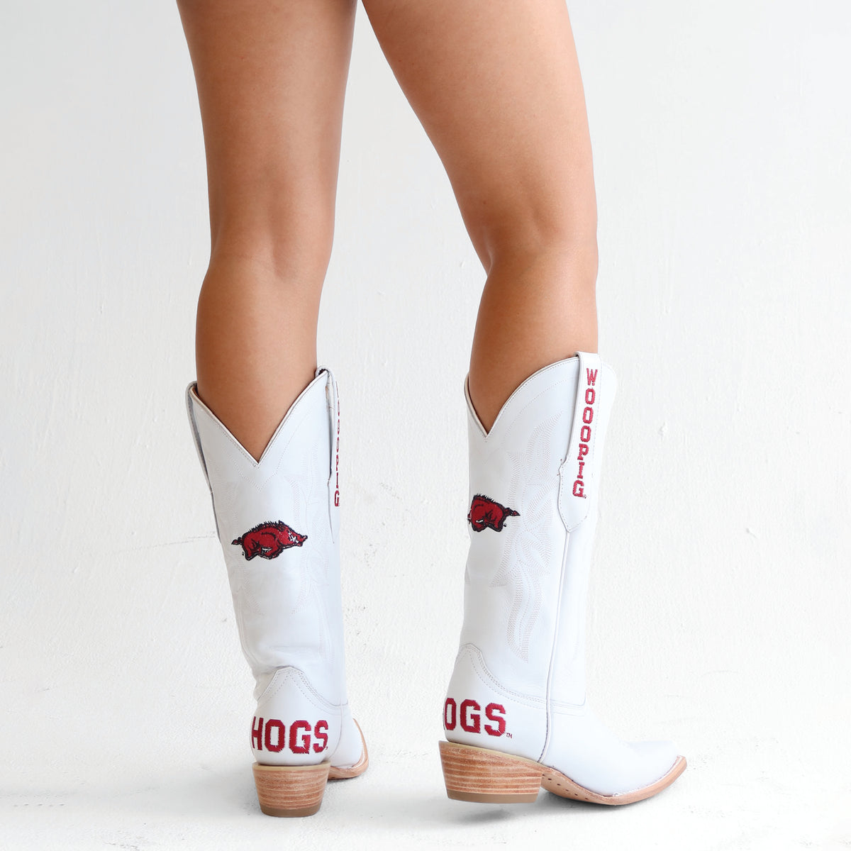 Pair of white cowboy boots with red lettering and hog graphic, stacked wooden heel