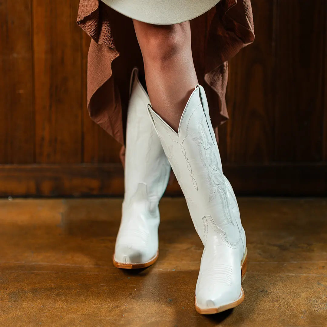 White cowboy boots on feet with brown stacked heels and western embroidery