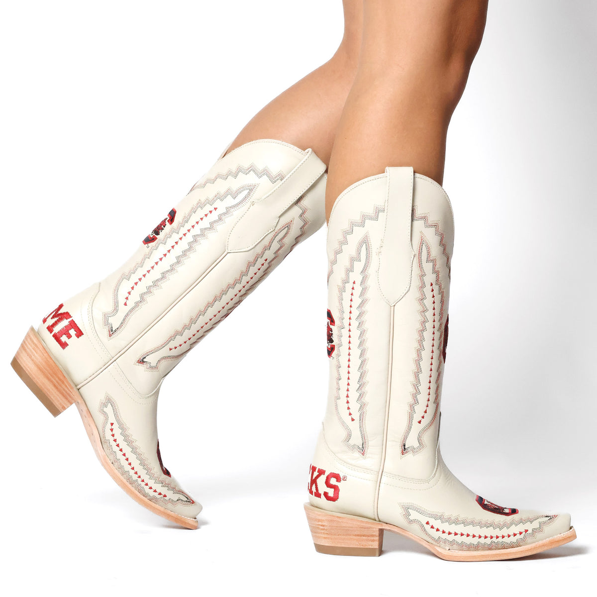 Pair of cream cowboy boots with red stitching, western patterns, and block heels