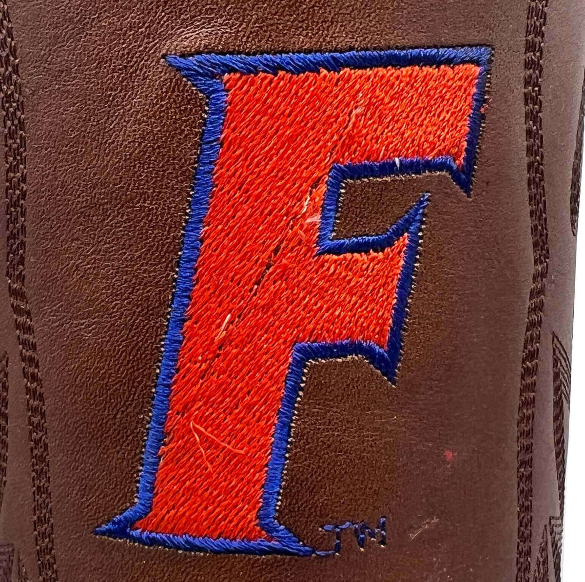 Brown leather boot with large red-and-blue embroidered letter on the side