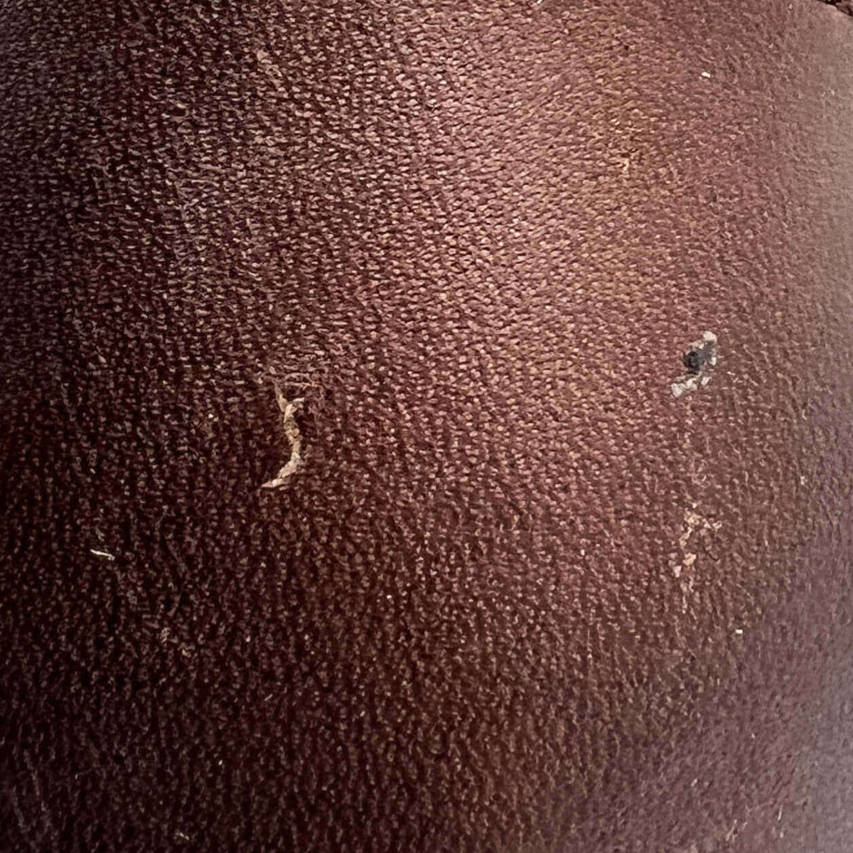 Brown leather boot shaft panel with small scuffs and surface wear