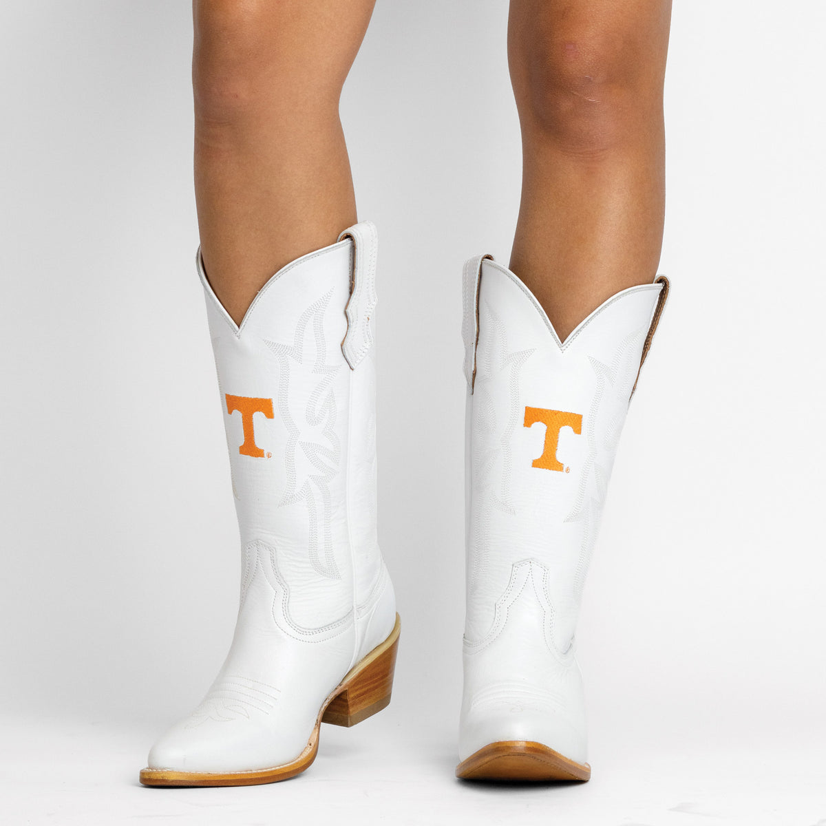 Leighton white cowboy boots with orange T logo, tan outsole, and stitched detailing