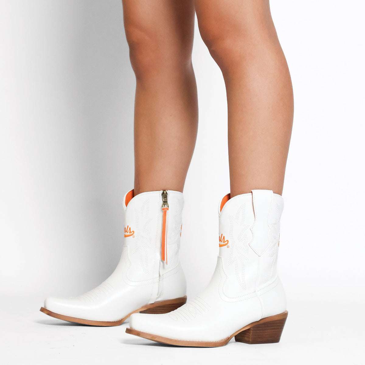 White cowboy boots with orange zipper pull and western stitching, block heel